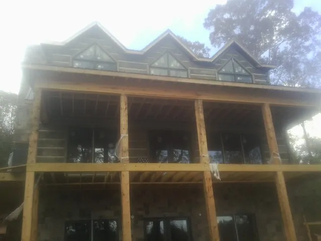 Dormers and porch framing on a large log home under construction — Roof Coating work by our crew in Hughesville