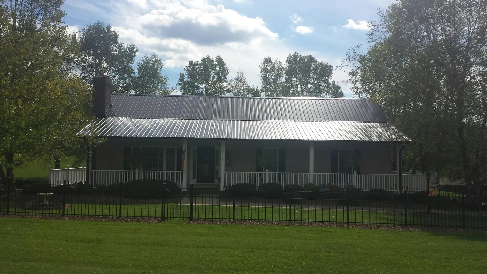 Gray metal roof on a brick ranch with a full width front porch — Gutter Guard Installation work by our crew in Hughesville