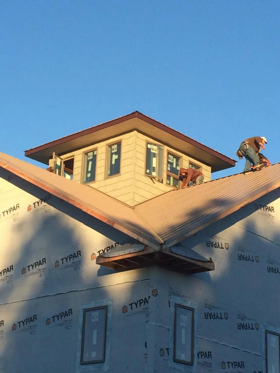 Roofers working around a rooftop cupola on a new metal roof at sunset — Roof Waterproofing in Hughesville by Roofing Brothers